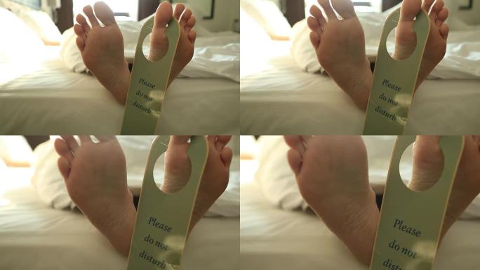 人的脚放在床上，上面有“请勿打扰”的标志