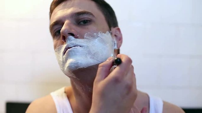 男人在浴室镜子前刮胡子