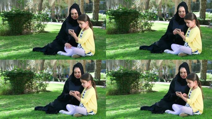 阿拉伯母女在公园玩智能手机