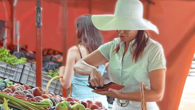 女人为她在市场摊位上挑选的苹果买单