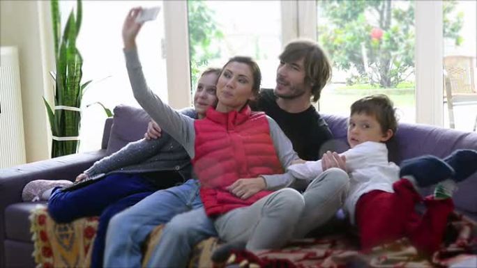 快乐的年轻家庭在家里用智能手机自拍