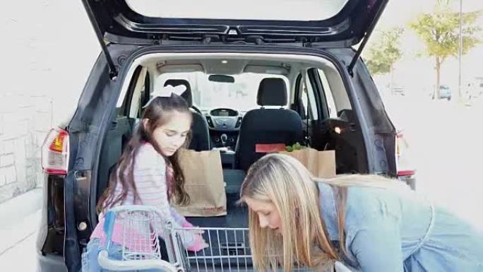西班牙裔小学时代的女儿正在帮助母亲在杂货店外的小型货车或SUV中装载牛皮纸食品杂货袋