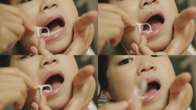 妈妈用牙线、特写、浅DOF为孩子清洁牙齿。
