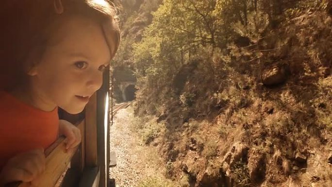 火车上的孩子-一个小女孩喜欢乘火车的第一次旅行。窗外的山景。