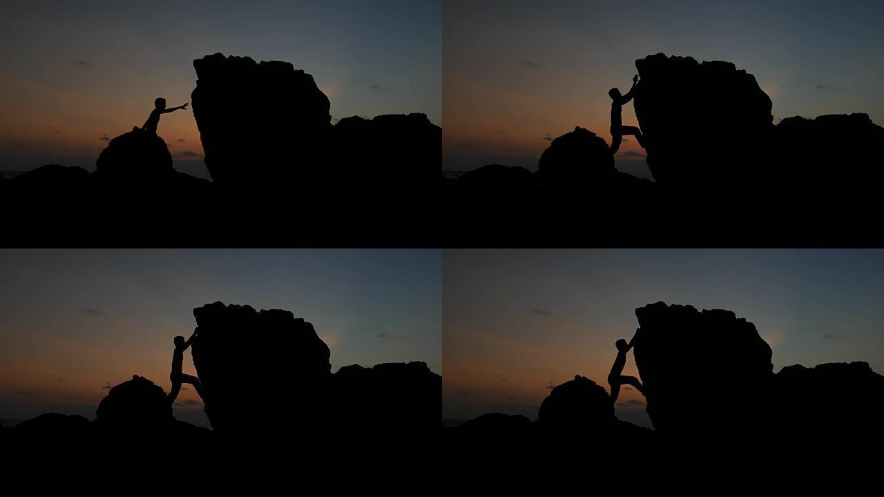 日落时岩石上男人的剪影