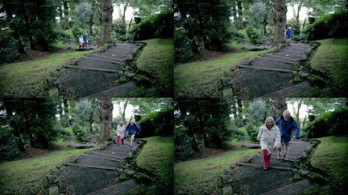 一对老年夫妇在树木繁茂的花园里走上台阶