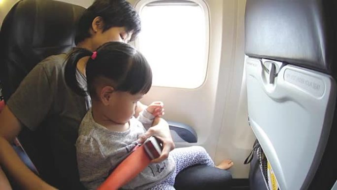 高清: 母亲在飞机上系好女儿的安全带