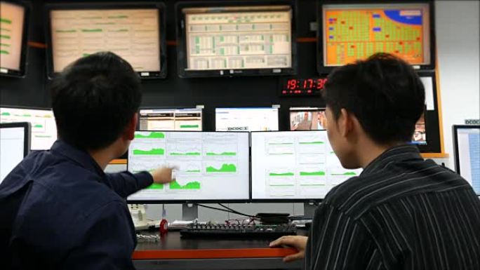 两名警官在监控室的计算机屏幕上注意到警报