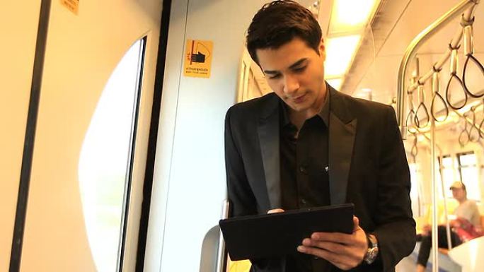高清: 年轻商人在火车上玩平板电脑。