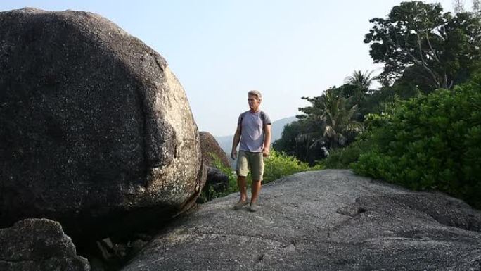 男子在丛林巨石之间徒步旅行，眺望远方