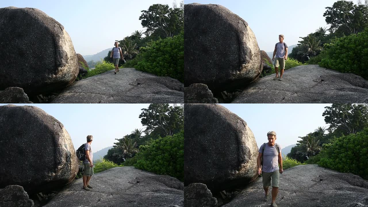 男子在丛林巨石之间徒步旅行，眺望远方