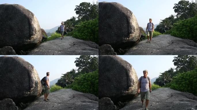 男子在丛林巨石之间徒步旅行，眺望远方