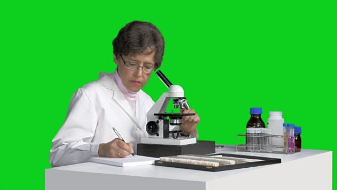 用显微镜观察并做笔记的女科学家
