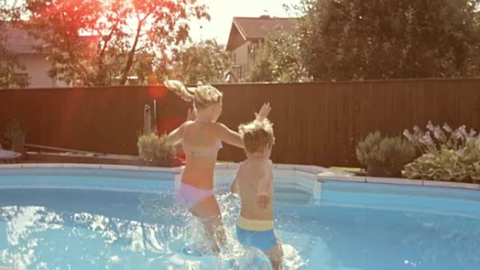 SLO MO DS兄弟姐妹在阳光明媚的日子跳进游泳池