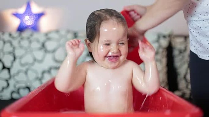婴儿洗澡。妈妈洗她的长发