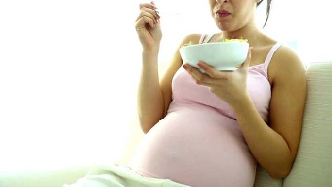 孕妇在家放松，吃沙拉零食。