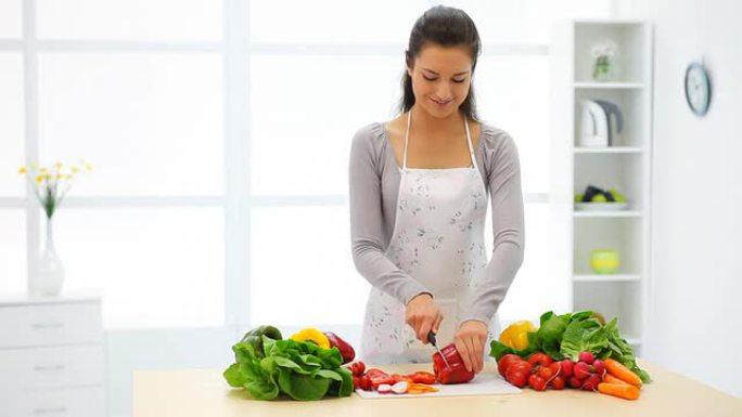 年轻女子在厨房切蔬菜。