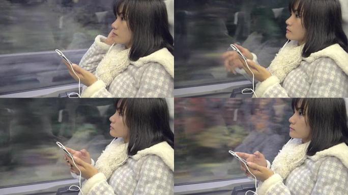 火车上的年轻亚洲妇女从手机上听音乐