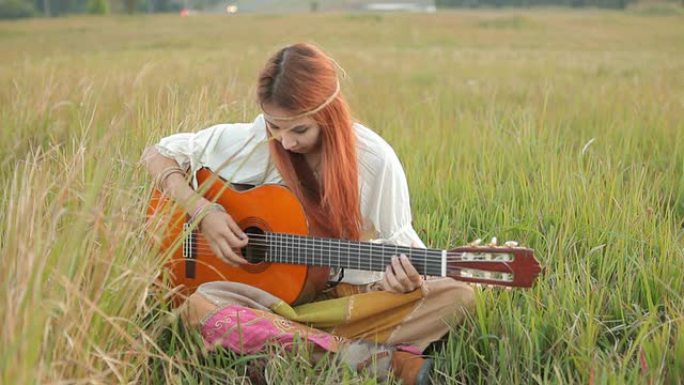 嬉皮士女孩在草地上弹吉他