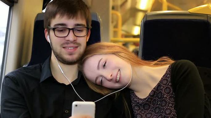 一对年轻的情侣在火车上听音乐。