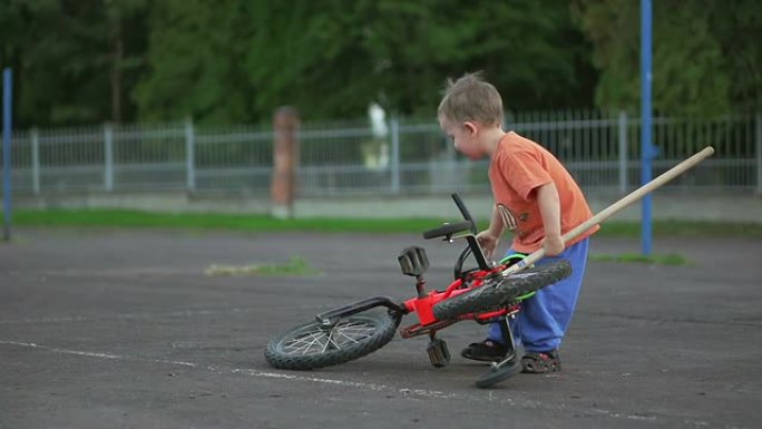 男孩摔倒后捡起自行车。