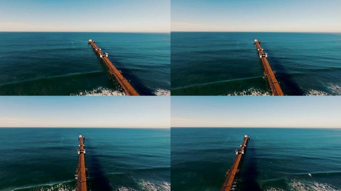 当码头似乎永远进入蓝色深渊时，美丽的日出在海洋上闪闪发光。