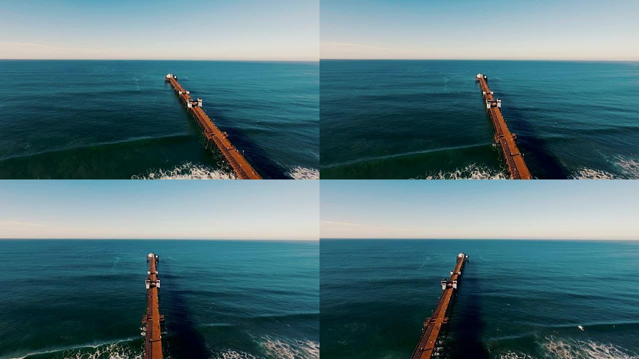 当码头似乎永远进入蓝色深渊时，美丽的日出在海洋上闪闪发光。