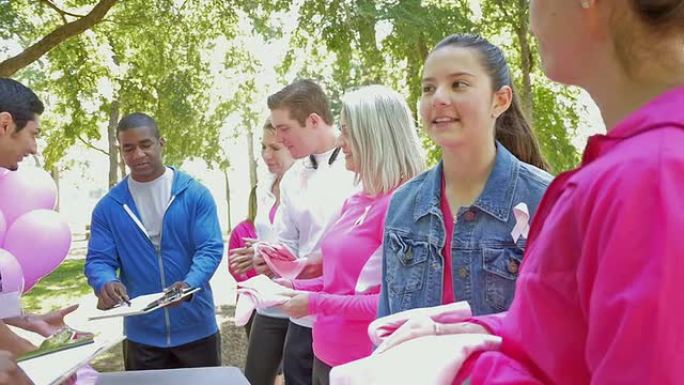 志愿者向报名参加乳腺癌意识马拉松的人分发t恤和比赛编号