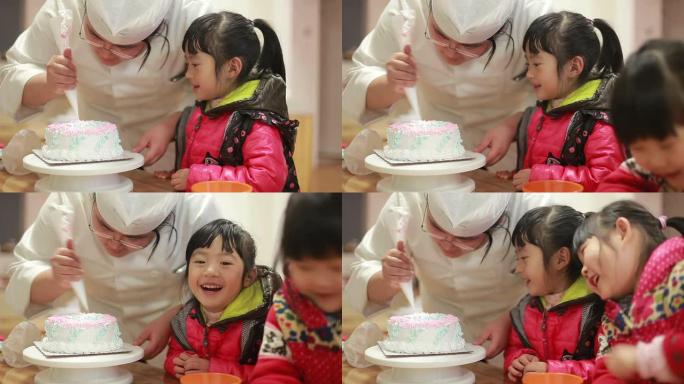 可爱的中国女婴手表厨师在生日蛋糕上滚边奶油