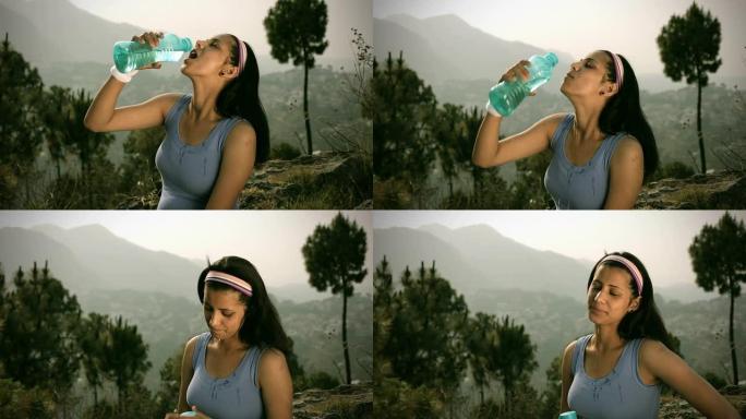 年轻女子在大自然中健身后喝水