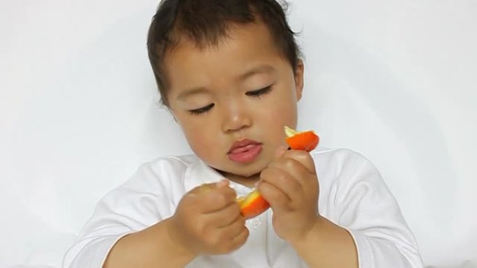 亚洲孩子认真地撕扯着橘子果肉，嘴唇抽搐