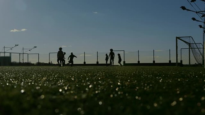 日落时踢足球的年轻人