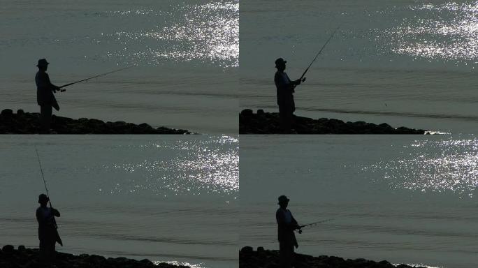 男子在海湾钓鱼海边钓鱼剪影水面反光