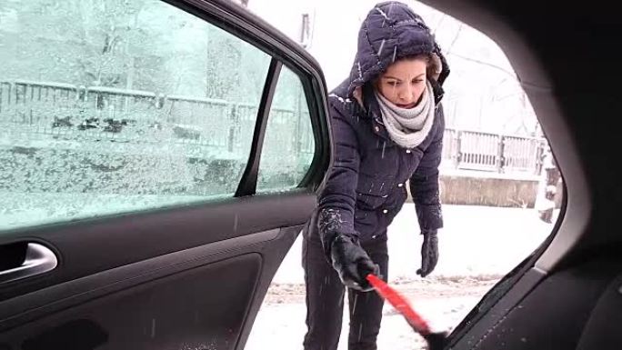 年轻女子清除汽车上的积雪。