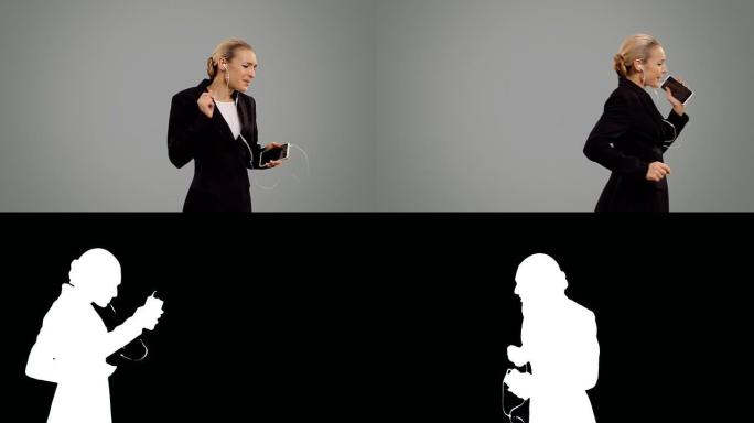 年轻的女商人在灰色屏幕上欣赏音乐和舞蹈。