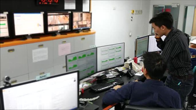 两名警官在监控室的计算机屏幕上注意到警报