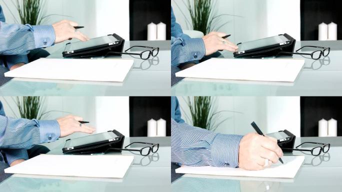 高清：男子使用数字平板电脑，然后在纸上写字