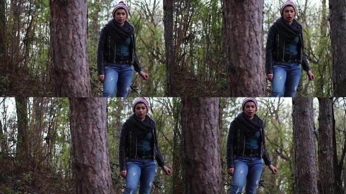 一个自信的年轻女孩在树林里的树木之间看着相机