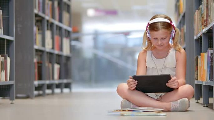 坐在图书馆过道上的DS年轻女孩在平板电脑上浏览