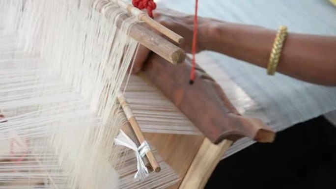 女人在手工织布机中以传统方式编织丝绸。泰国