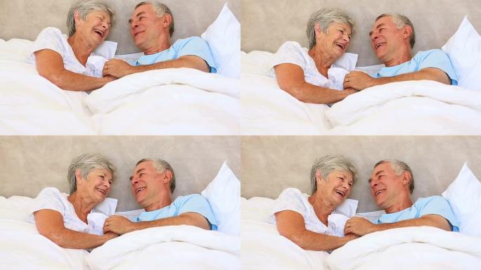 幸福的老年夫妇躺在床上聊天