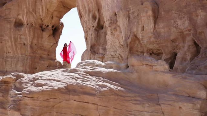 穿着红色连衣裙站在岩石上的女孩