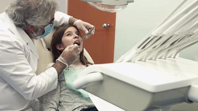 牙医用牙科椅上的器械检查女孩的嘴