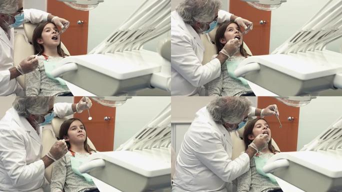牙医用牙科椅上的器械检查女孩的嘴