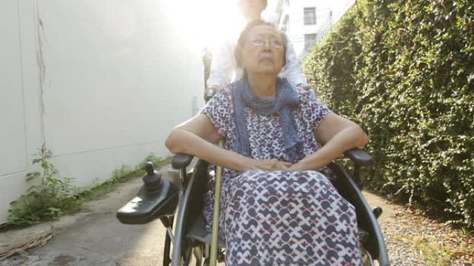 年轻的看护人照顾坐在轮椅上的老年妇女