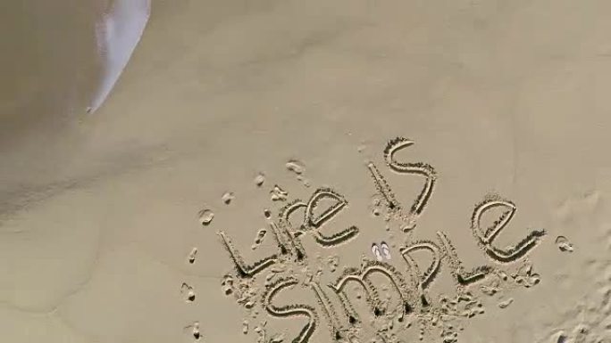在海滩上写的 “生活很简单” 的俯视图