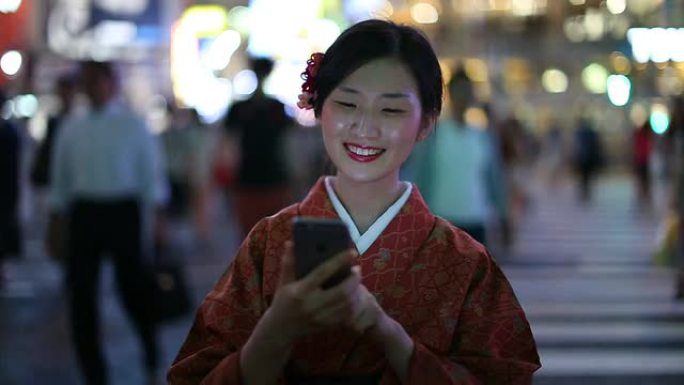 穿着和服的日本女孩在涩谷发短信微笑