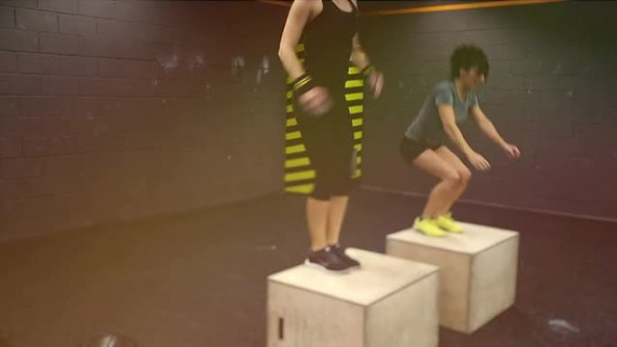 两名年轻女子在健身房跳跳箱