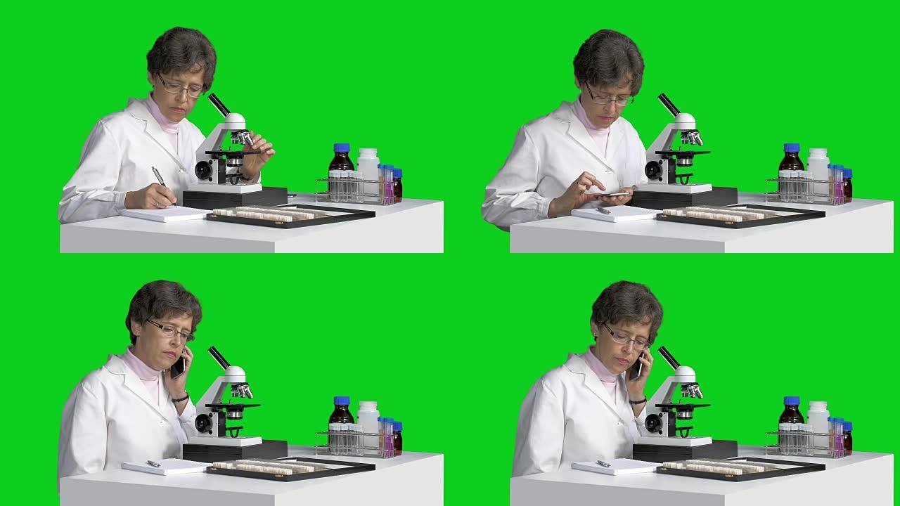 用显微镜观察女性科学家用手机做笔记和打电话