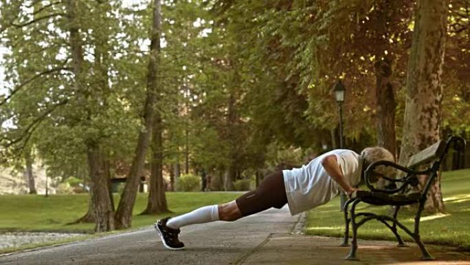 DS高级男运动员在公园长椅上做俯卧撑